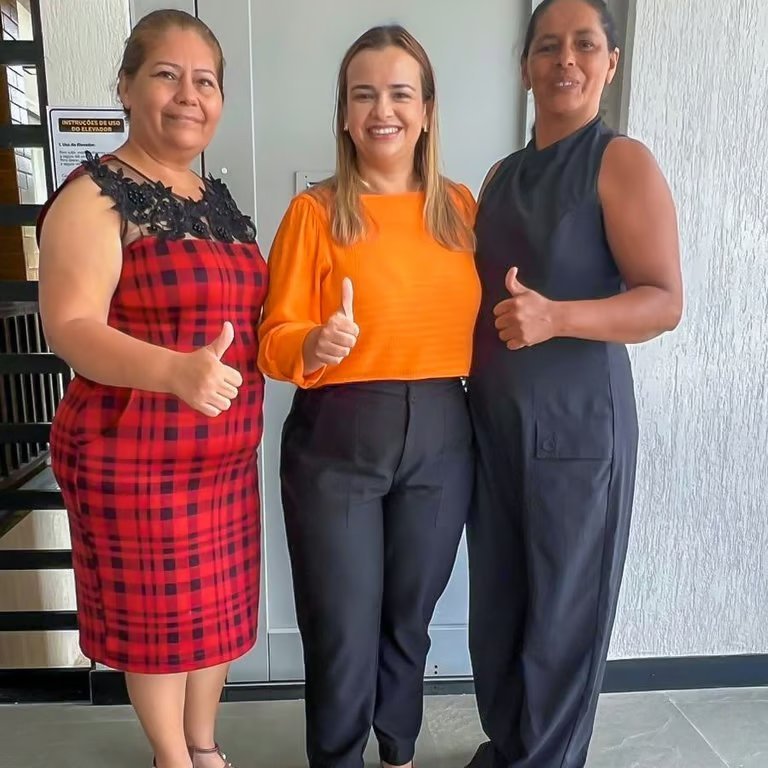Paulinha Braga entre duas apoiadoras durante encontro na comunidade